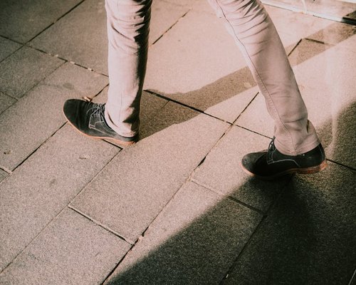 Person walking slowly on a sidewalk